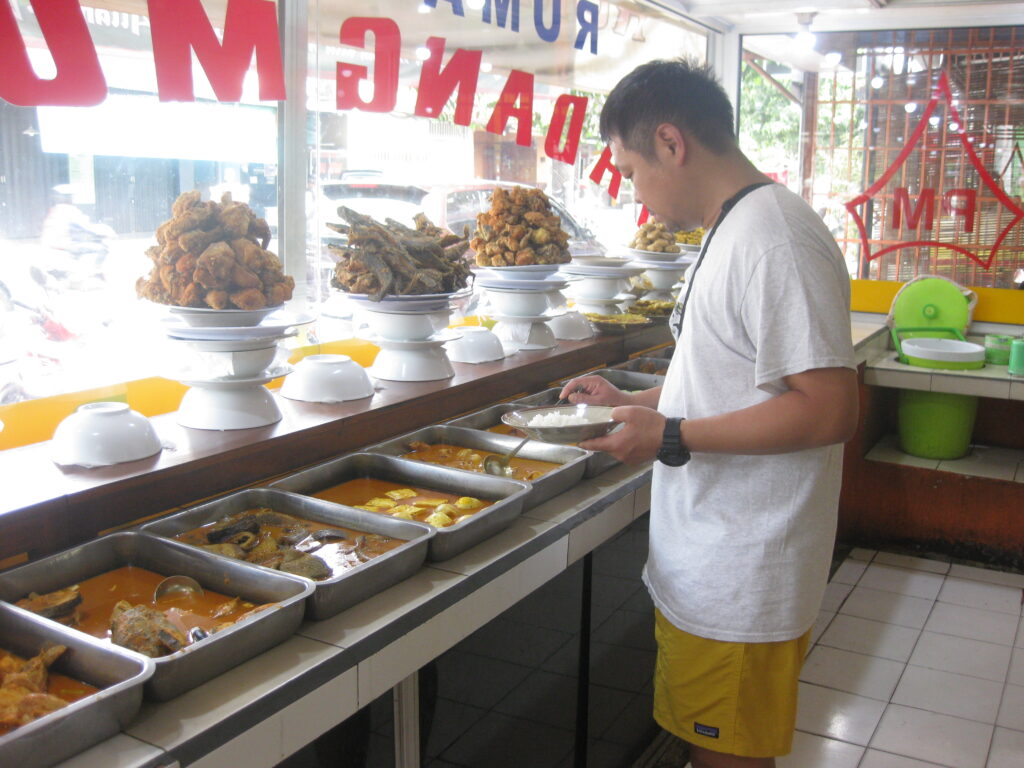 ワルン店内で食べ物をバイキングしている男性を撮影した写真